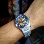 Relógio Orient Skeleton automático: estilo sofisticado com fundo azul/dourado e correia prateada para quem busca elegância. - Imagem 3