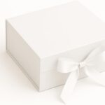 Caixa de Presente Premium Branca: rígida, com trava magnética e laço de cetim para presentear com elegância e segurança.
